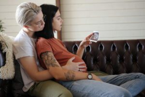 Imagem ilustrativa de casal de mulheres abraçadas com uma das mulheres gestantes