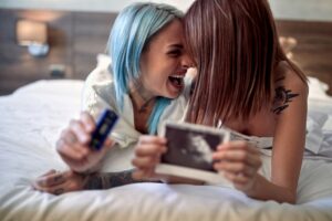 Casal de mulheres sorrindo pela chegada de um filho.