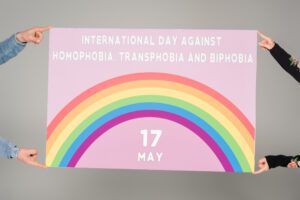 Pessoas seguranco cartaz que fala sobre o dia internacional de combate a homofobia.